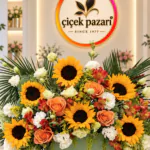 Ada çayı yeşili kutuda ayçiçeği, turuncu gül ve beyaz çiçeklerden aranjman