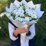 Sivri uçlu beyaz ambalajda beyaz papatya ve okaliptus buketi