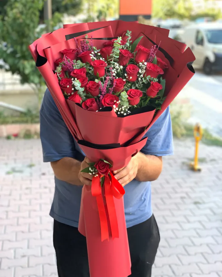 Mat kırmızı uzun ambalajda kırmızı gül, cipso ve okaliptus buketi; kurdele üzerinde tek gül