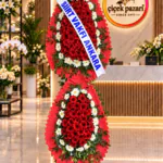 Fırfırlı kırmızı çerçeveli iki katlı ferforje; kırmızı gerberalar, beyaz gerbera halkası ve kurdele
