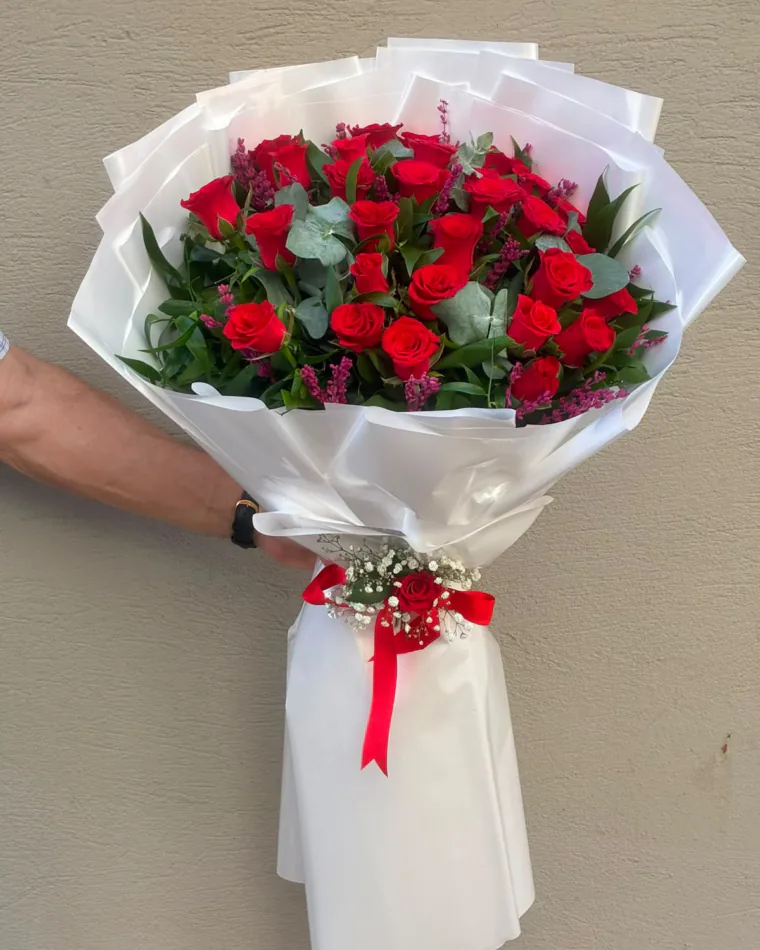 İnci beyazı ambalajda kırmızı gül ve okaliptus buketi; kurdele üzerinde tek gül ve cipso