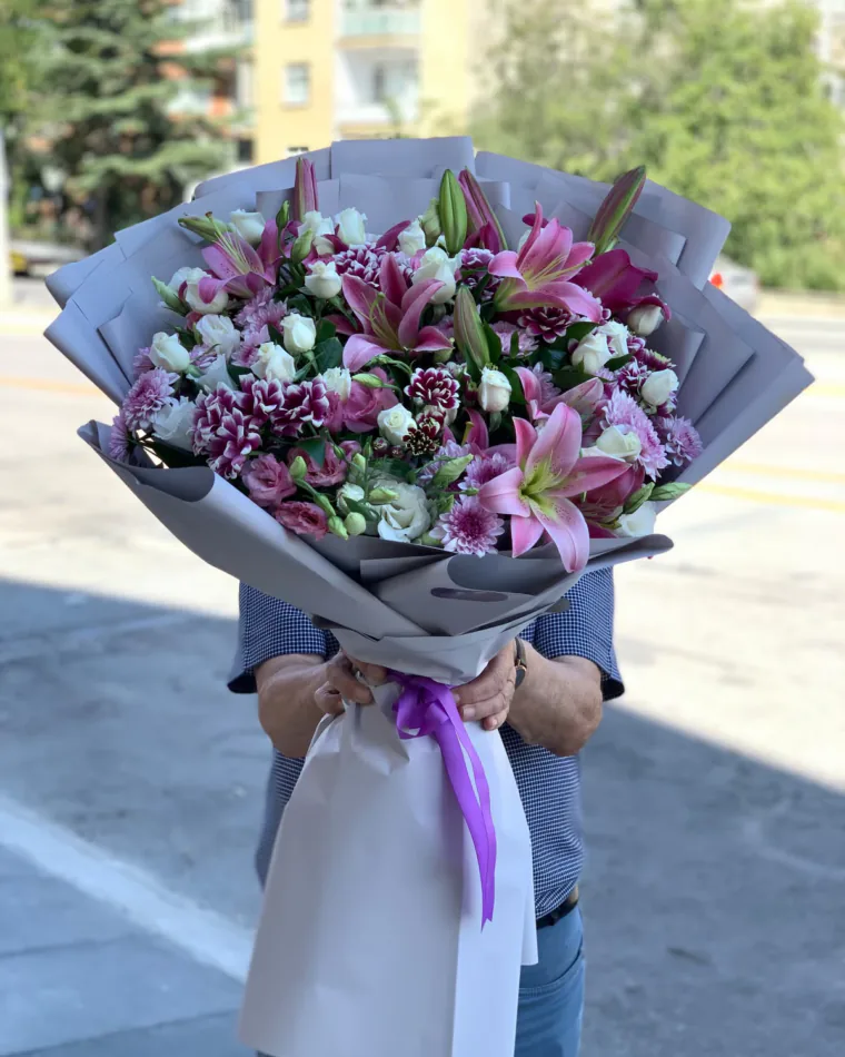 Gri ambalajlı büyük buket; pembe lilyum, bordo-beyaz krizantem, beyaz gül ve mor saten kurdele