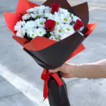Kırmızı ve siyah ambalajda beyaz papatya ve kırmızı gül buketi, kırmızı saten kurdele